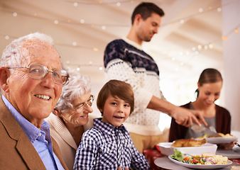 Image showing Grandparents, portrait and family at dinner on Christmas, together with food and celebration in home. Happy, event and kid smile with old man at lunch and relax on holiday at table with grandmother