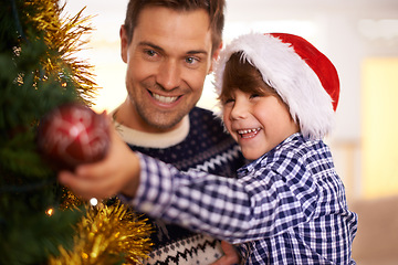 Image showing Tree, decoration and dad with child at Christmas with happiness on holiday or vacation. Festive, event and kid helping father and smile with ornament in home for merry celebration with family