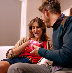 Image showing Couple, surprise and present in lounge of home, happiness and together for anniversary in house. Man, smile and giving gift to girlfriend with love in living room of house, woman and shock with wow