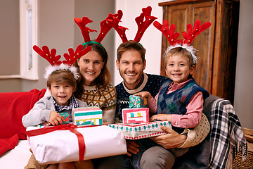 Image showing Portrait, smile and family with present for Christmas, holiday or together at festive celebration on sofa at home. Xmas, parents and happy children with gift in living room, face or antlers at party