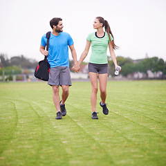 Image showing Couple, holding hands and walk in park for workout, chat and training for wellness with bag in summer. People, man and woman for support, care or bonding on lawn for exercise for fitness in England