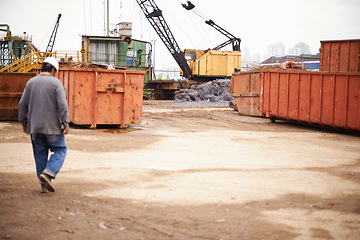 Image showing Crane, machine and engineer man in junkyard to recycle metal for sustainability, manufacturing or pollution. Vehicle, tractor and outdoor in scrapyard for ecology with back, industry and environment