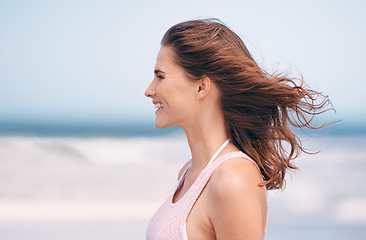 Image showing Woman, wind and smile on beach environment for holiday destination or travel journey, happiness or blue sky. Female person, relax and seaside in Florida for outdoor paradise, fresh air or adventure