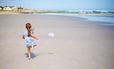 Image showing Child, beach and running with fishing net or nature explore in summer or vacation adventure, environment or rear view. Female person, kid and seaside in Florida for holiday destination, ocean or trip