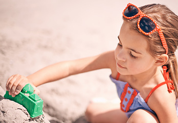 Image showing Girl, toys and building sandcastle on the beach with shape or block for fun summer, holiday or weekend in nature. Female person, child or kid playing and enjoying sand construction by the ocean coast