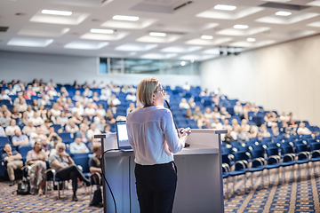 Image showing Female speaker giving a talk on corporate business conference. Unrecognizable people in audience at conference hall. Business and Entrepreneurship event.