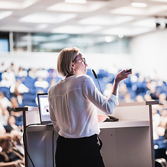 Image showing Female speaker giving a talk on corporate business conference. Unrecognizable people in audience at conference hall. Business and Entrepreneurship event.