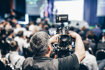 Image showing Speaker giving a talk in conference hall at business event. Rear view of unrecognizable people in audience at the conference hall. Business and entrepreneurship concept.