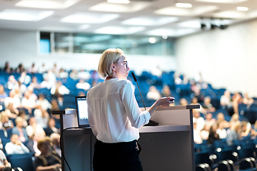 Image showing Female speaker giving a talk on corporate business conference. Unrecognizable people in audience at conference hall. Business and Entrepreneurship event.