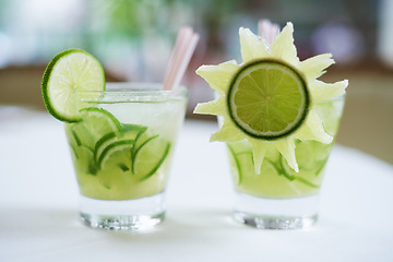 Image showing Cocktail, alcohol and mojito with lime for drink on table for party, club and bar decoration. Glass, background and closeup of mocktail, beverage and liquid with fruit, ice and liquor in restaurant