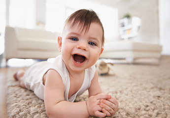 Image showing Happy, baby portrait and tummy time on floor, laugh and play in living room. Teething, child development and growth learning to crawl by laying on stomach, curious kid in white vest for at home fun