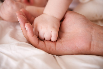 Image showing Bed, holding hands and parent with infant, health and support with maternity, bonding and wellness at home. Fingers, family and love with a baby, protection and child development with bonding or care