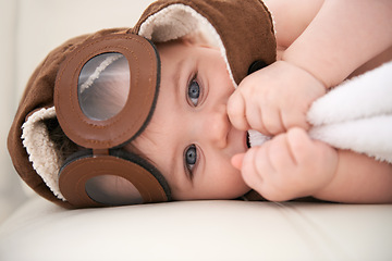 Image showing Baby, portrait and pilot hat or happy at home on bed for childhood development for growth, blanket or comfortable. Kid, boy and face airplane flying accessory in apartment for peace, relaxing or rest