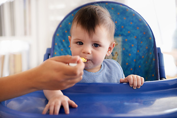 Image showing Baby, hand and spoon for feeding food in chair for morning nutrition in apartment for eating meal, development or lunch. Kid, childcare and fingers for toddler dinner or wellness, hungry or vitamins