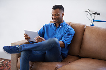 Image showing Man, tablet and relax on social media at home, online and internet for website or blog. Black male person, smile and streaming entertainment on armchair, video call and app for shopping on weekend