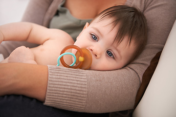 Image showing Baby, parent and relax in arms with pacifier for childhood development or growth safety with love, caring or resting. Kid, dummy and together in apartment for bonding support, security or comfort