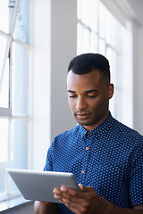 Image showing Businessman, tablet and internet at window for communication, online search or networking in office. Entrepreneur, african employee and serious with technology for corporate email or planning at work