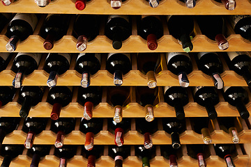 Image showing Wine cellar, bottle and storage on rack in vineyard for restaurant stock, winery and shelf with alcohol display. Warehouse, drinks collection and beverage stack in basement with arrangement and row