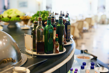 Image showing Sauce, bottles and condiment in restaurant for food with hospitality industry for dining. Catering, cuisine and plate of flavors selection on counter for lunch, dinner or supper meal in cafeteria.