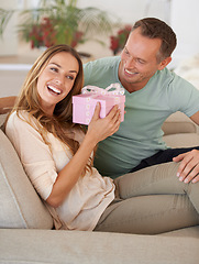 Image showing Woman, surprise or gift for man in lounge, excited or happy couple to celebrate love in home. Husband, care and guessing with present for wife, gratitude and bonding together on sofa for anniversary