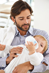 Image showing Bonding, bottle and father feeding baby for child development or growth in living room at home. Love, sweet and young dad holding infant, toddler or kid drinking milk in lounge at modern house.