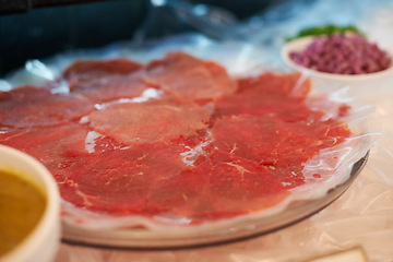 Image showing Carpaccio, closeup and food on plate for dinner with appetizer, fine dining and buffet of raw meat in restaurant. Beef, seafood and protein meal on table for nutrition, snack or lunch at social event