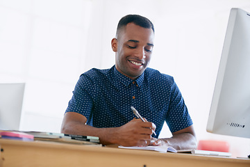 Image showing Computer, research and man writing notes in office for creative project on internet by desk. Technology, smile and professional male designer working online with desktop in modern workplace.