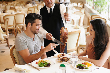 Image showing Happy couple, date and dining with kebab of waiter serving, meat or slices on romantic dinner at table. Young man or woman with chef, skewer or food for meal, eating or enjoying service at restaurant