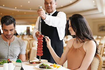 Image showing Couple, fine dining and waiter serving food or sausage kebab on skewer or restaurant, anniversary or nutrition. Man, woman and relationship bonding dates in Italy with water carving, meal or eating