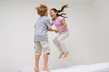 Image showing Jumping, bed and kids with laugh, happy and morning in a bedroom with game and sibling. Youth, bonding and home with excited children in air with crazy, play and funny joke with energy and friends