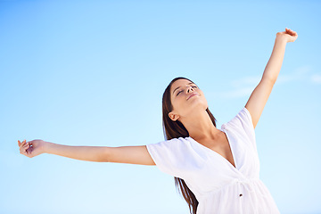 Image showing Blue sky, sunshine and woman on holiday with freedom, happy adventure and low angle in Greece. Summer, smile and calm girl stretching arms for energy, wellness and outdoor travel vacation in nature