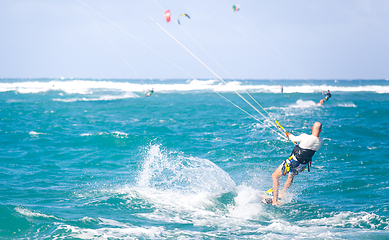 Image showing Kiteboarding. Fun in the ocean. Extreme Sport Kitesurfing. Kitesurfer jumping high in the air performing triks during kitesurfing session.