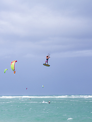 Image showing Kiteboarding. Fun in the ocean. Extreme Sport Kitesurfing. Kitesurfer jumping high in the air performing triks during kitesurfing session.