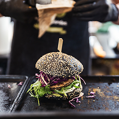 Image showing Chef making healthy vegetarian salmon burgers outdoor on open kitchen, odprta kuhna, international food festival event. Street food ready to be served on a food stall.