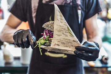 Image showing Chef serving vegetarian salmon burgers outdoor on open kitchen, odprta kuhna, international food festival event. Street food being served on a food stall.