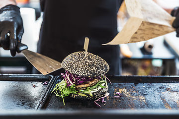 Image showing Chef making healthy vegetarian salmon burgers outdoor on open kitchen, odprta kuhna, international food festival event. Street food ready to be served on a food stall.