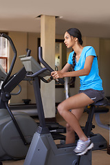 Image showing Woman, cardio and exercise bike in gym, active and stationary machine for workout at club. Female person, body health and cycling for strength training, challenge and equipment for fitness or action