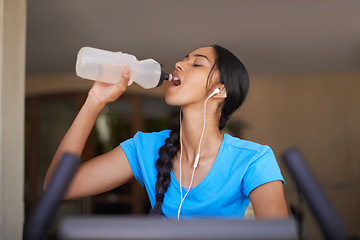 Image showing Woman, water and exercise bike in gym, cycling and stationary machine for workout at club. Female person, earphones and hydrate for strength training, music and equipment for fitness and body health