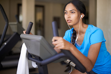 Image showing Woman, earphones and music for cycling, bike and stationary machine for workout at club. Female person, cardio and inspirational podcast for motivation, playlist and equipment for fitness and health