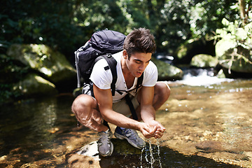 Image showing Hiking, nature and man by river drinking water for thirst on adventure, trekking and explore outdoors. Travel, camping and person by lake or stream for wellness on holiday, vacation and journey