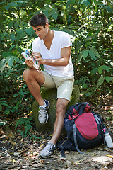 Image showing Man, map and reading for hiking in forest with search for thinking, holiday or ideas on path. Man, woman and bag for trekking, direction and guide in tropical jungle with book at location in Colombia