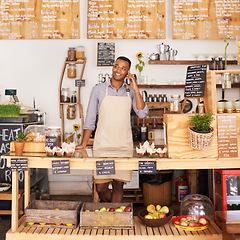 Image showing Thinking, smile and phone call with black man in coffee shop for communication, networking or service. Cafe, restaurant and small business with happy young store owner or vendor working in bakery