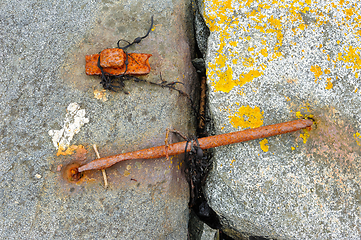 Image showing Rusty metal anchor secured in weathered stone pier by the sea