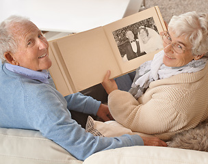 Image showing Senior couple, portrait or looking at photo album together, pictures or memories at home, living room or couch. Elderly people, top view or cheerful on sofa with wedding photographs, happy or smiling