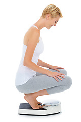 Image showing Woman, happy and scale in studio for weight loss, healthcare and wellness for vitality. Female person, diet and check calories for slim body for self care, achievement and sit with white background