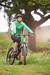 Image showing Woman, sports and fitness with bicycle on field for outdoor cycling, workout or cardio exercise in nature. Female person, athlete or cyclist in forest for off road training on green grass or trail