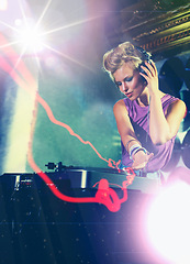 Image showing Woman, dj and turntable with headphones for music on stage with lens flare, mixing and gig at rave party for entertainment. Female sound mixer, artist and musician with record player for playlist