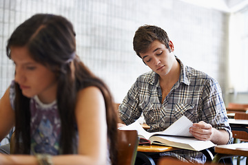 Image showing Studying, students and reading in textbook for information, test and knowledge for assignment in university. People, scholarship or concentration in college by desk or academic research for learning