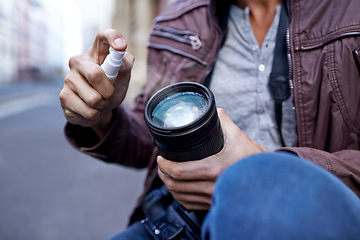 Image showing Hands, man and photographer with spray for camera lens to clean for work, create portfolio in streets of Berlin. Closeup, artist and picture in public space for career in media and creativity.