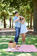 Image showing Love, picnic and surprise with couple in park for romance, bonding and summer vacation. Happiness, commitment and relax with man and blindfold woman in nature for date, support and relationship